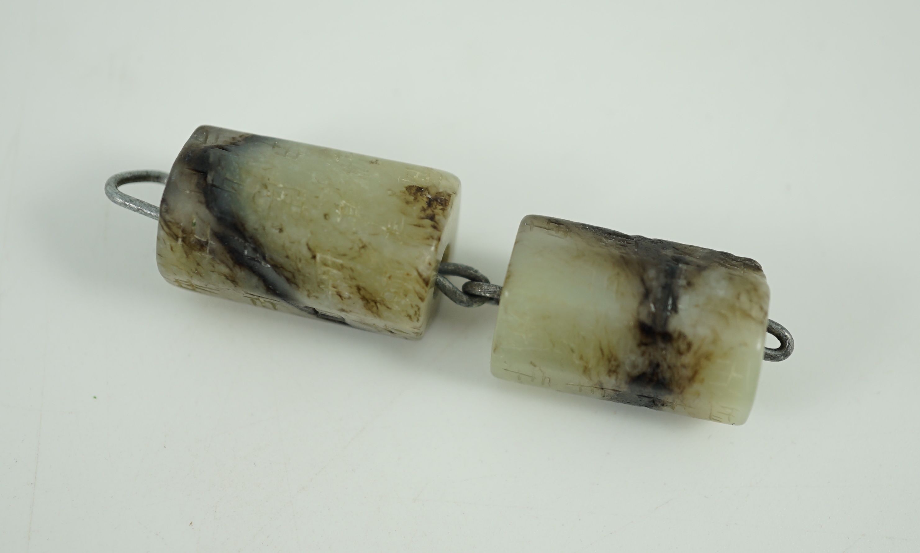 Two Chinese grey and black seal script inscribed jade beads, possibly Han dynasty, largest bead 2.5 cm